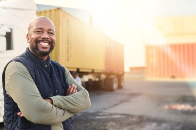 Man, portrait and arms crossed by truck, container stack and happy for transport job. Driver, smile and shipping cargo freight with happiness in transportation service, stock delivery or supply chain.
